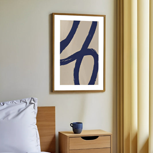 Framed  Minimalist abstract navy blue wall art print on a wall above a wooden nightstand with a blue cup.