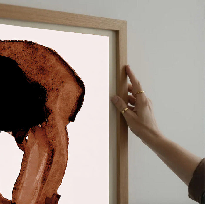 Person holding a wooden frame with a piece of wood art inside