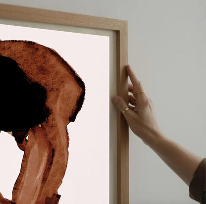 Person holding a wooden frame with a piece of wood art inside