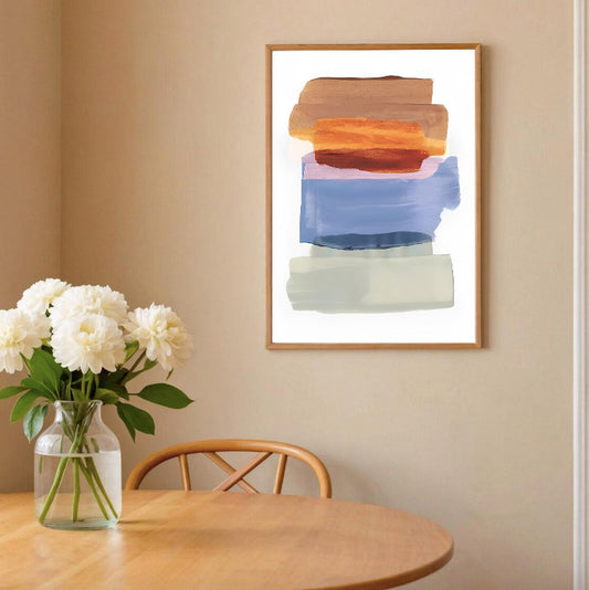 Framed abstract art on a wall above a wooden table with a vase of flowers.