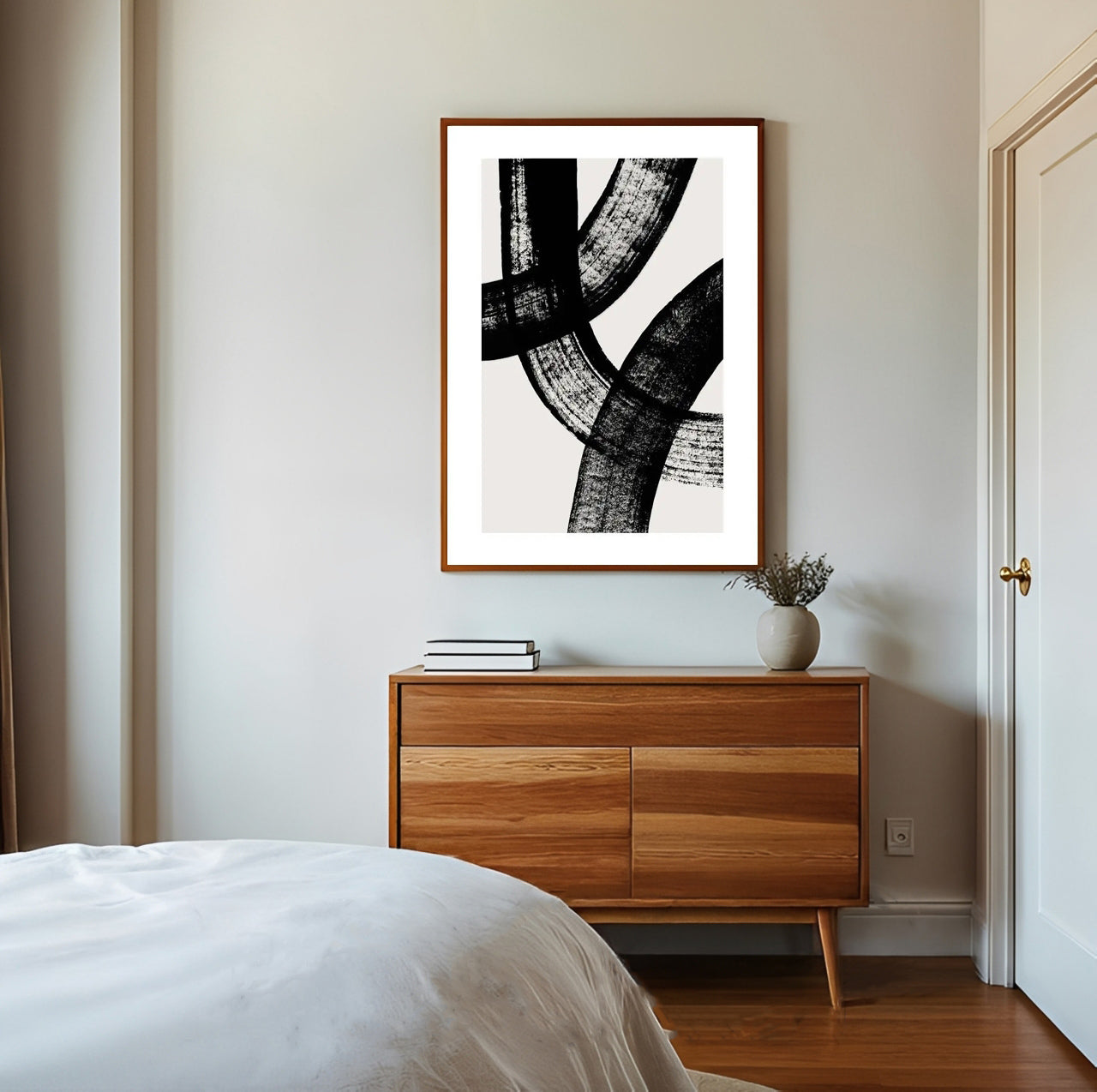 Abstract black and white artwork on a wall above a wooden dresser in a bedroom.