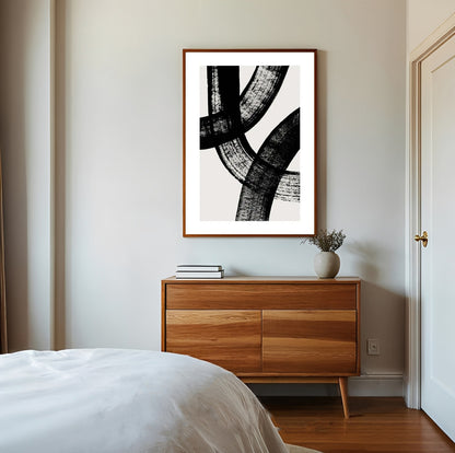 Abstract black and white artwork on a wall above a wooden dresser in a bedroom.