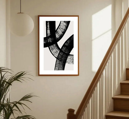 Framed abstract black and white artwork on a wall in a home setting with a staircase.