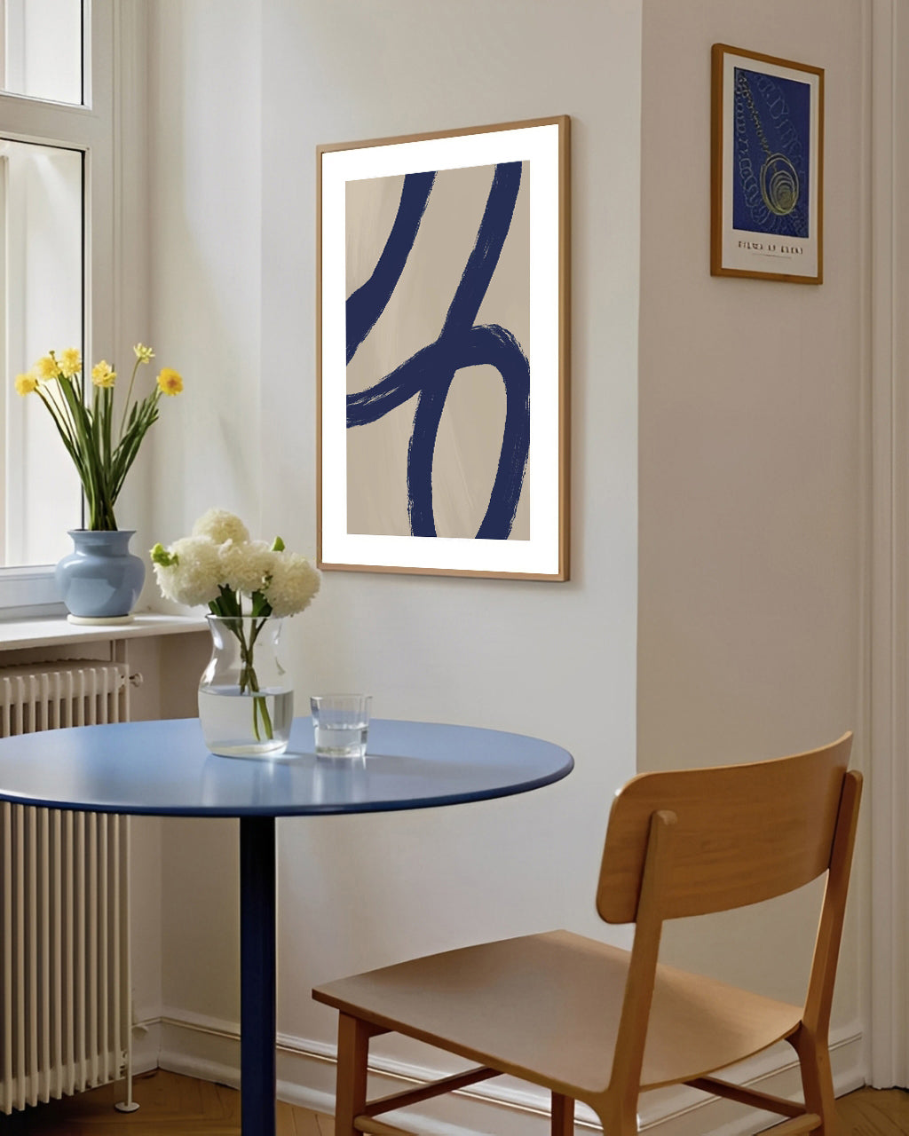 Small dining area with a blue table, wooden chair, and abstract art on the wall.