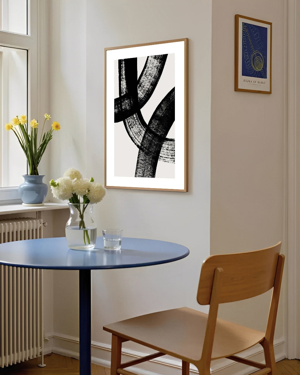 Dining room with a round blue table, wooden chair, and abstract art on the wall.