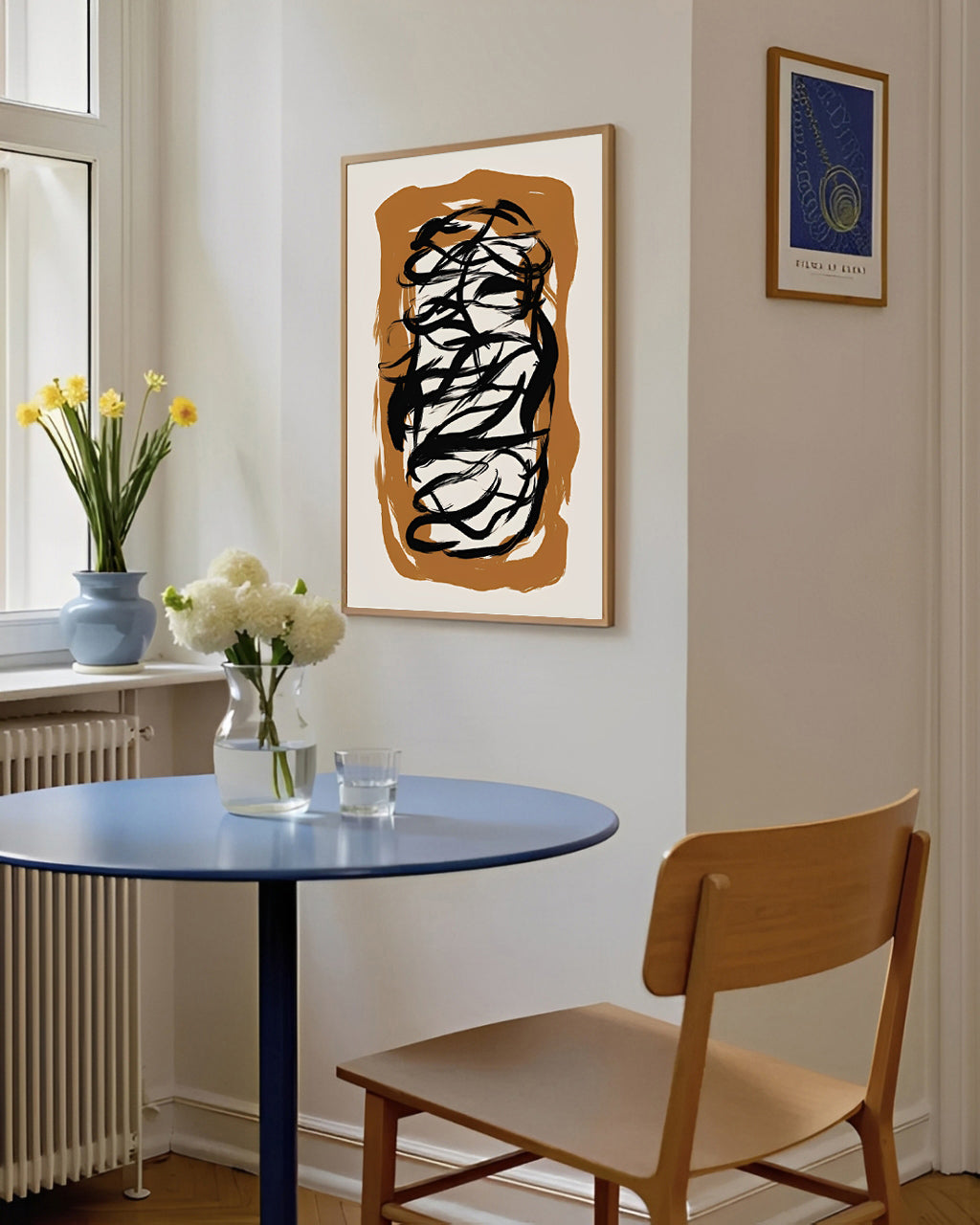 Small dining area with a round blue table, wooden chair, and abstract art on the wall.