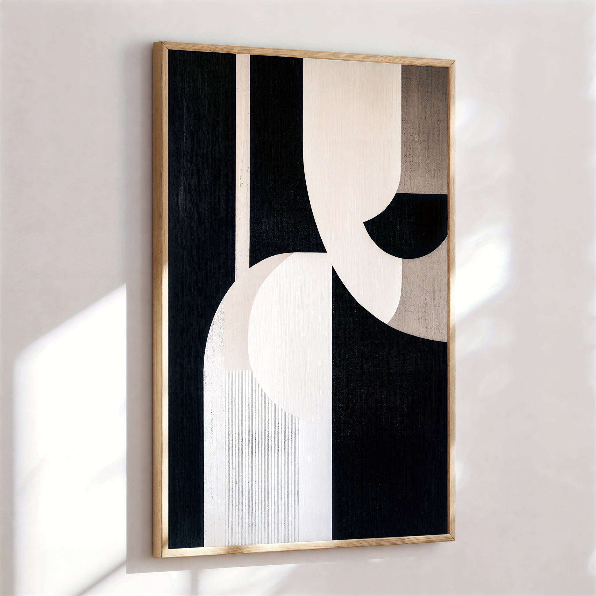 Abstract art piece with black, white, and beige colors in a wooden frame on a light wall.