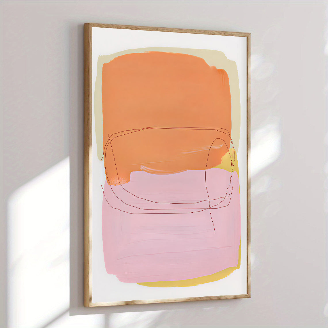 Abstract art print with orange and pink shapes in a gold frame on a light gray wall.