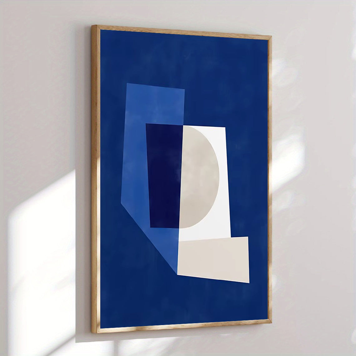Abstract art print with geometric shapes on a blue background, framed in wood, hanging on a white wall.