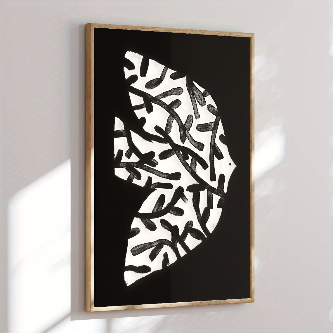 Framed abstract art print with black and white pattern on a wall.
