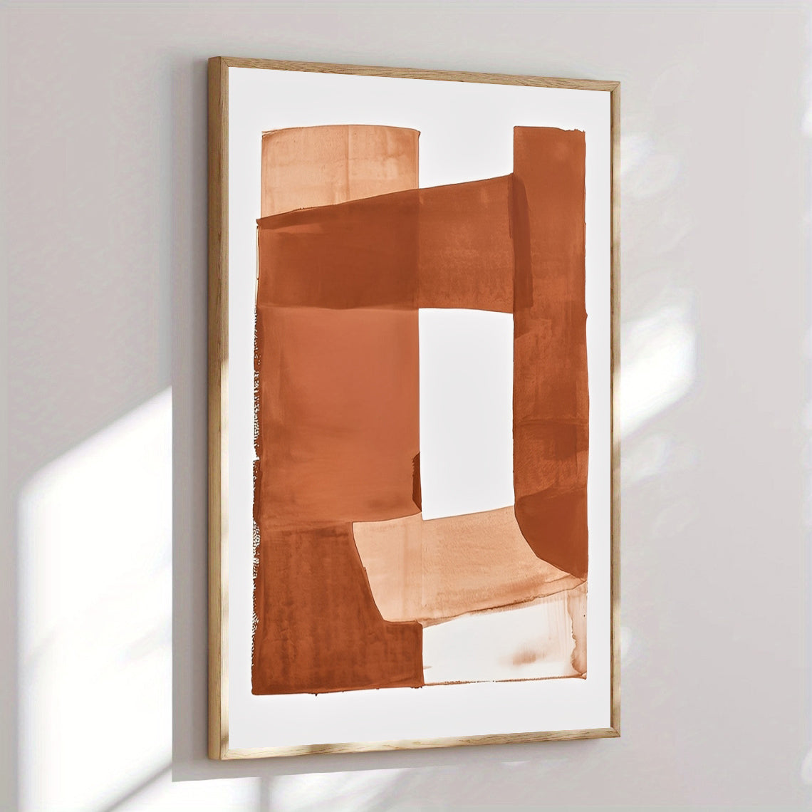Abstract art print with brown shapes in a gold frame on a white wall