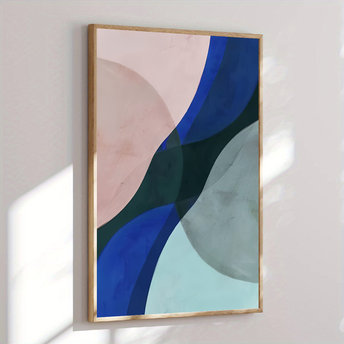 Abstract art print with blue, green, and pink shapes in a gold frame on a light wall.