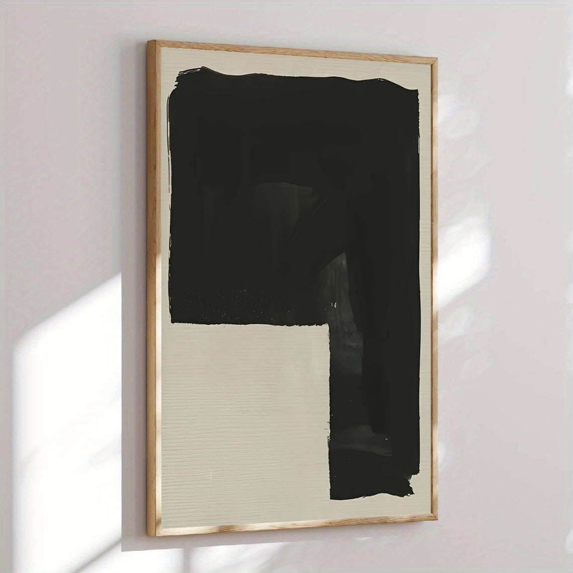 Abstract art piece with black and beige colors in a gold frame on a white wall.
