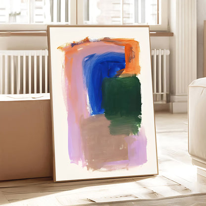 Abstract art print in a gold frame on a table with a light background