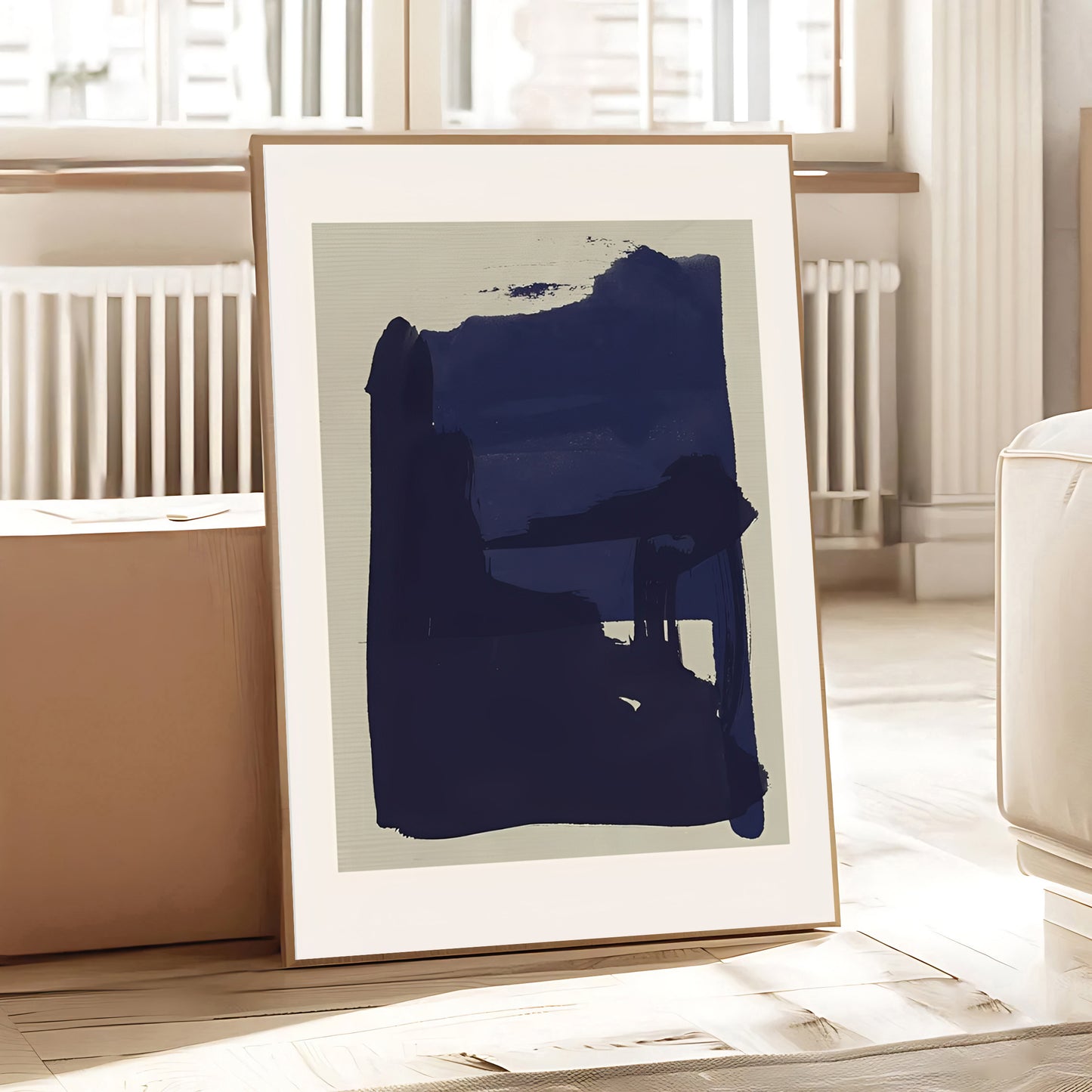 Framed abstract art print with a large blue brushstroke on a light background, placed in a room with a radiator and window.