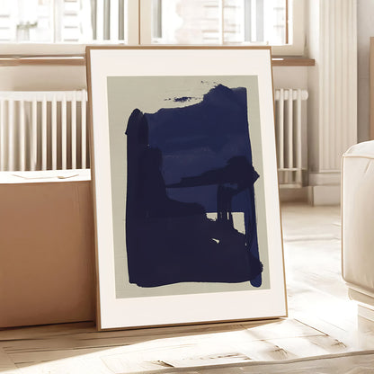 Framed abstract art print with a large blue brushstroke on a light background, placed in a room with a radiator and window.