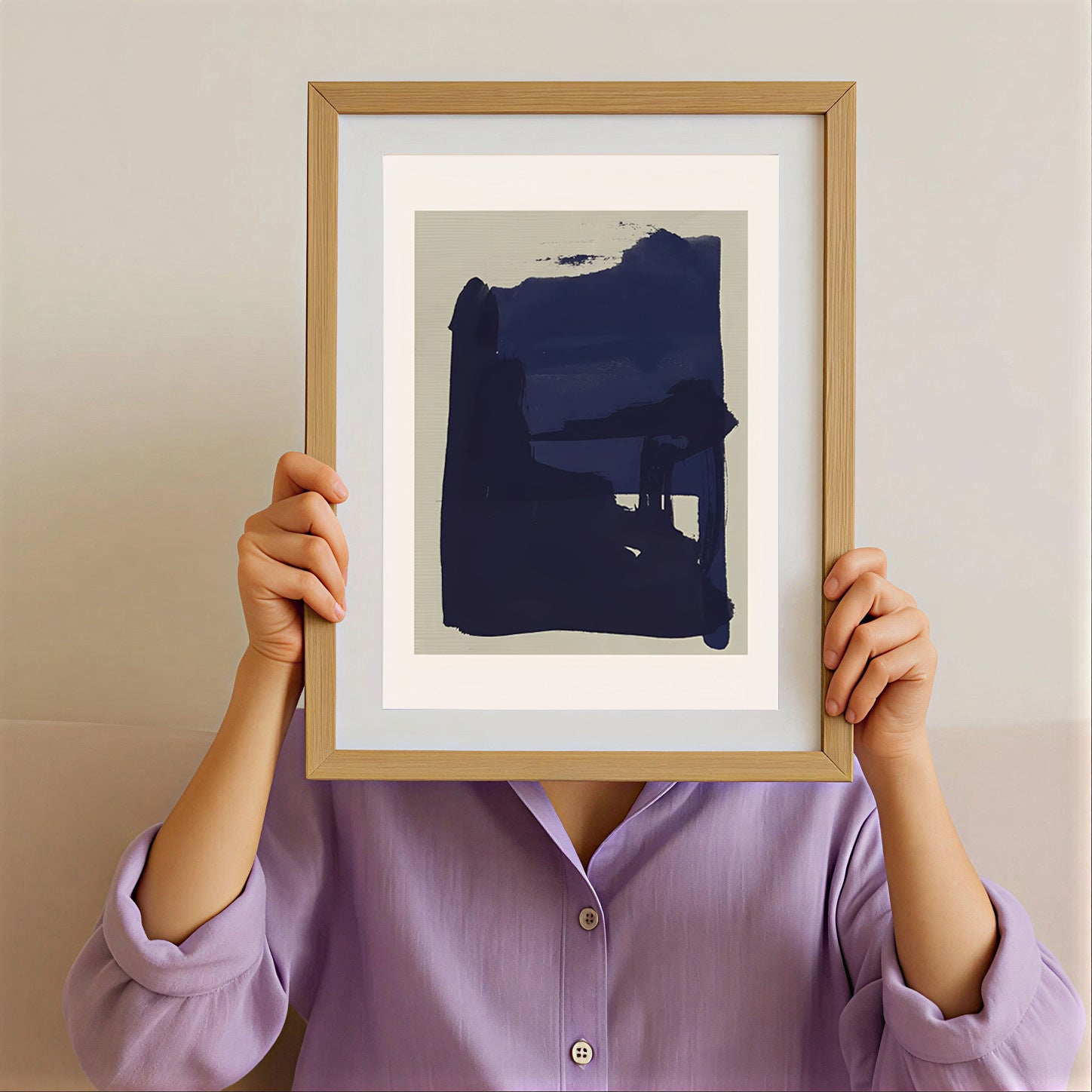 Person holding a framed abstract art print with a blue shape against a plain background