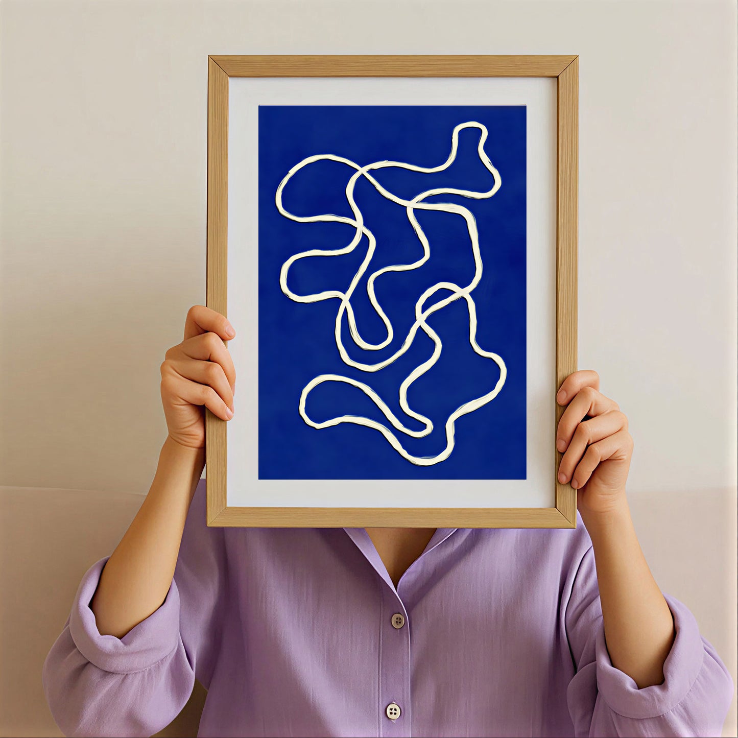 Person holding a framed abstract art print with blue background and white lines.