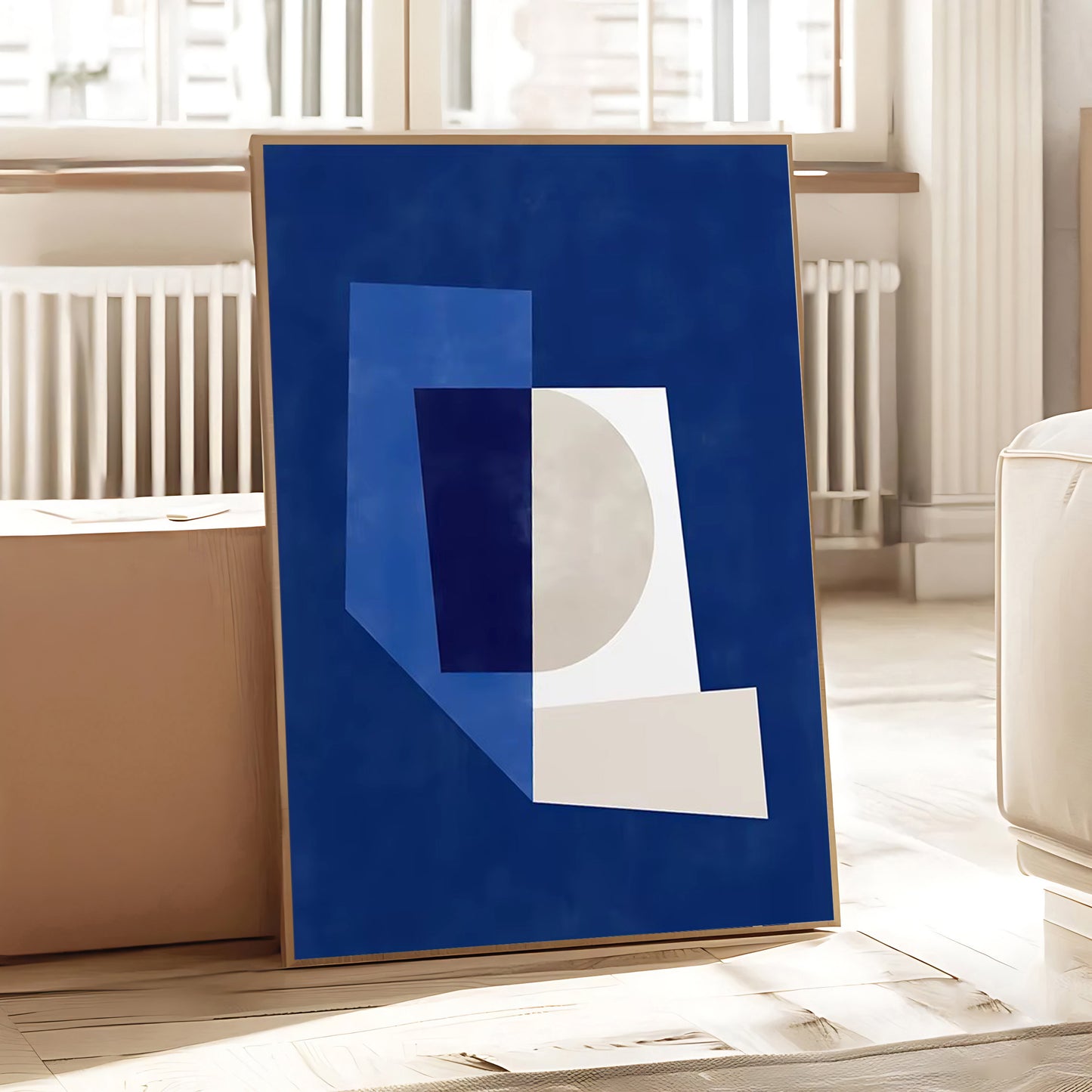Framed abstract art piece with geometric shapes on a blue background in a room.
