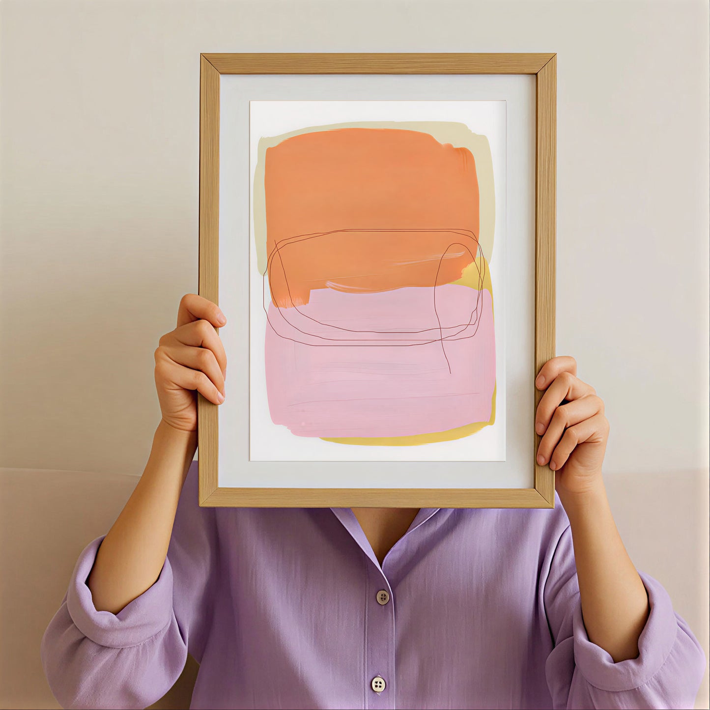 Person holding a framed abstract art print with orange and pink colors against a plain background