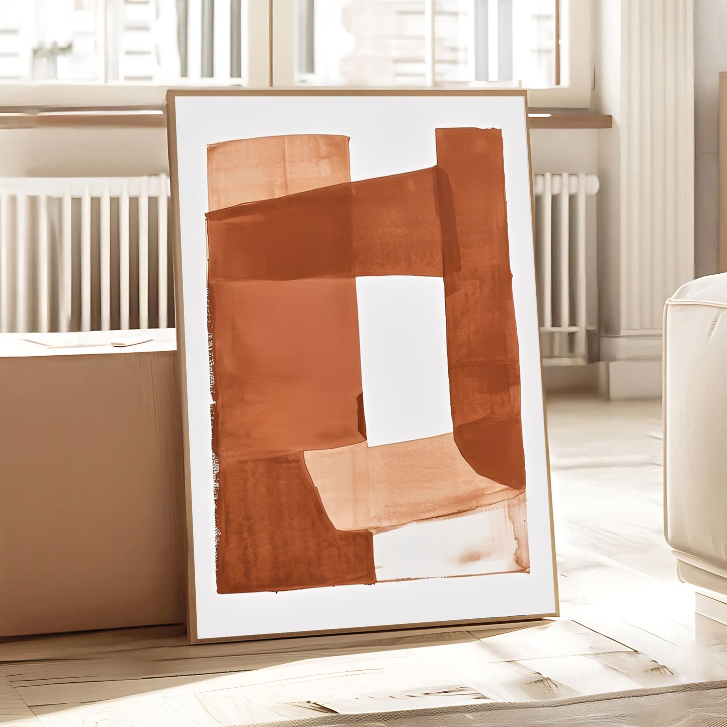 Framed abstract art piece with brown and beige colors on a light wooden floor.