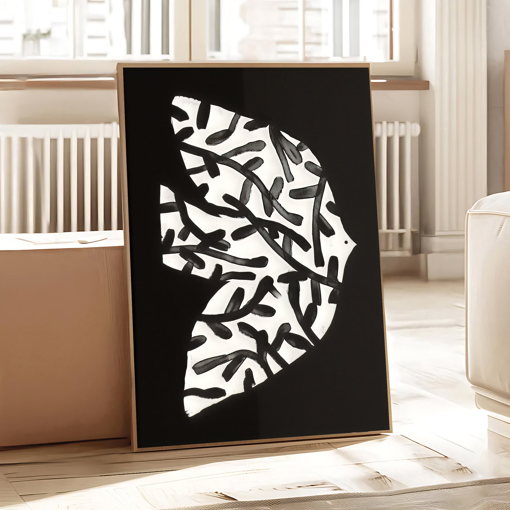 Framed abstract art piece with black and white design on a wooden floor.