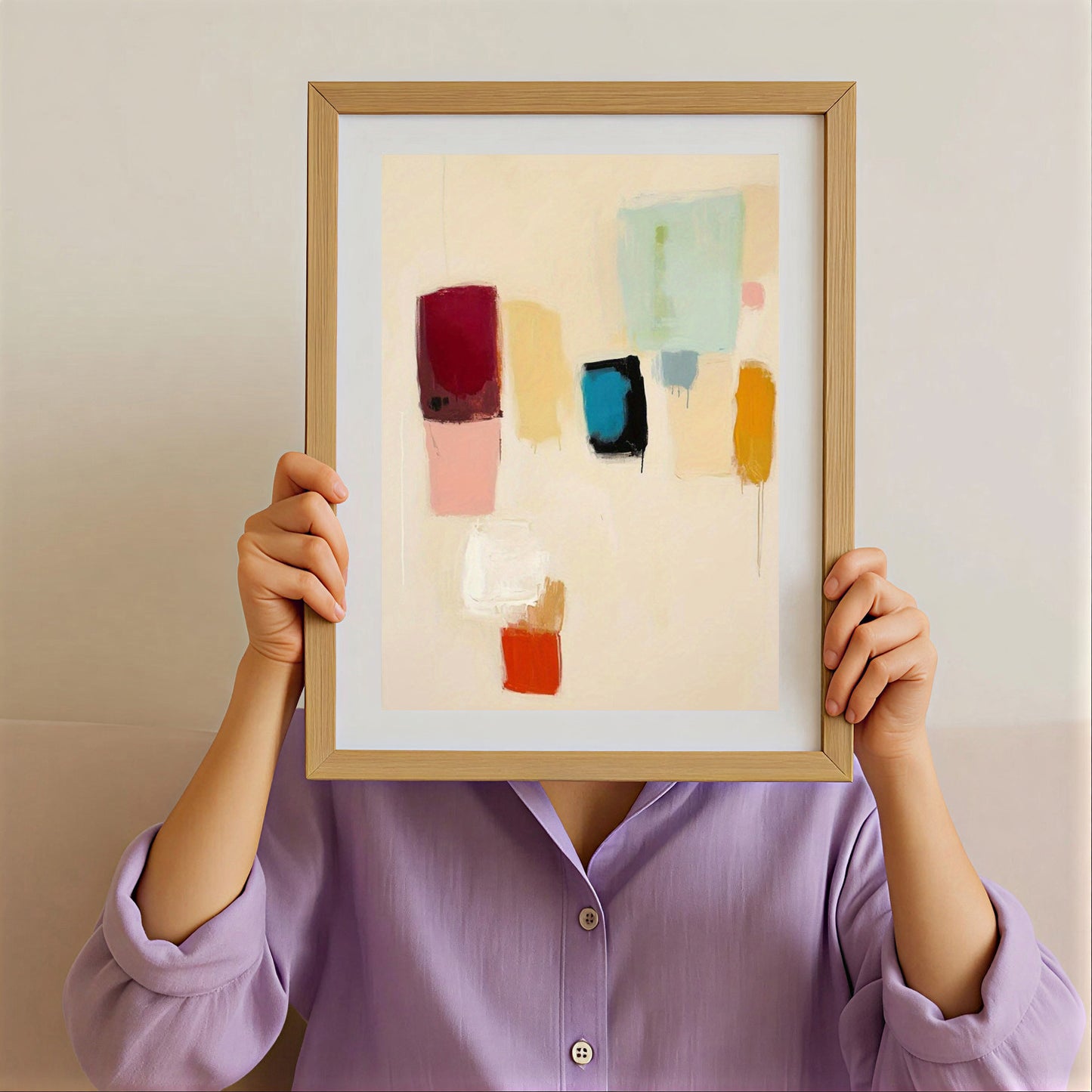 Person holding a framed abstract art piece with colorful blocks against a plain background