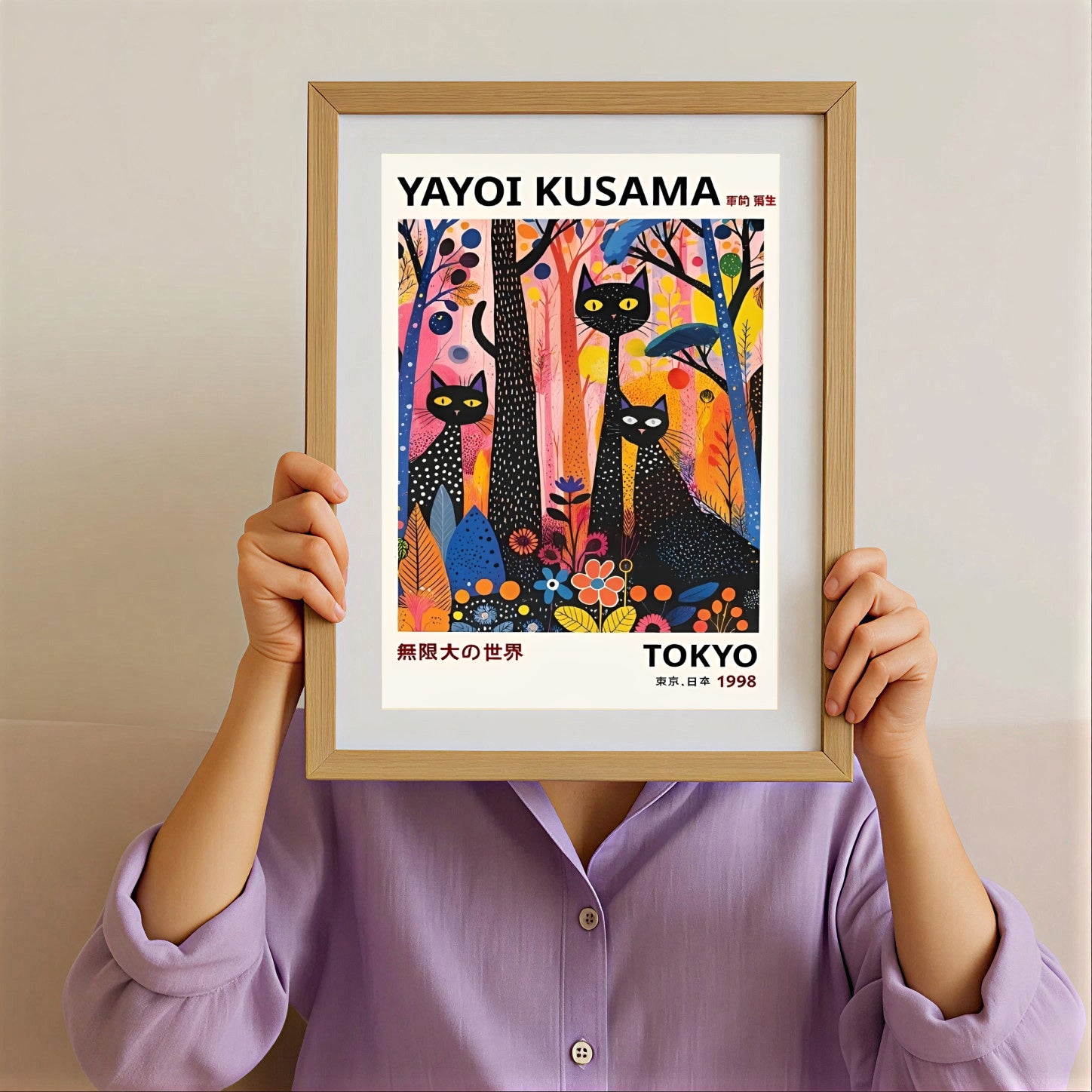 Person holding a framed Yayoi Kusama black cats artwork with colorful trees.