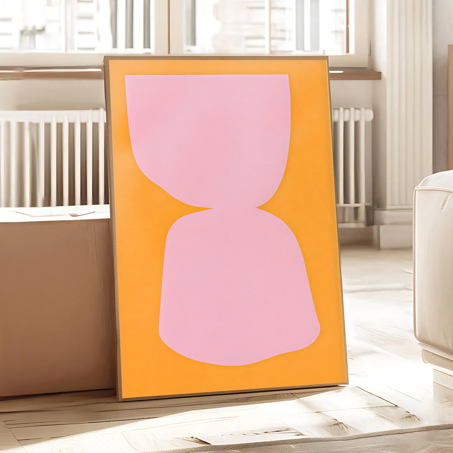 Framed abstract artwork with a pink shape on an orange background in a room.