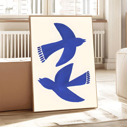 Framed artwork with blue bird silhouettes on a white background in a room.