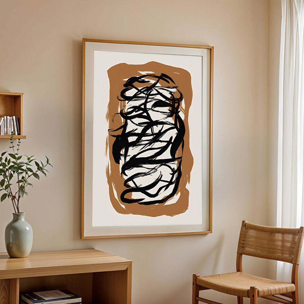 Abstract art piece in a wooden frame on a wall with a chair and shelf in the foreground.