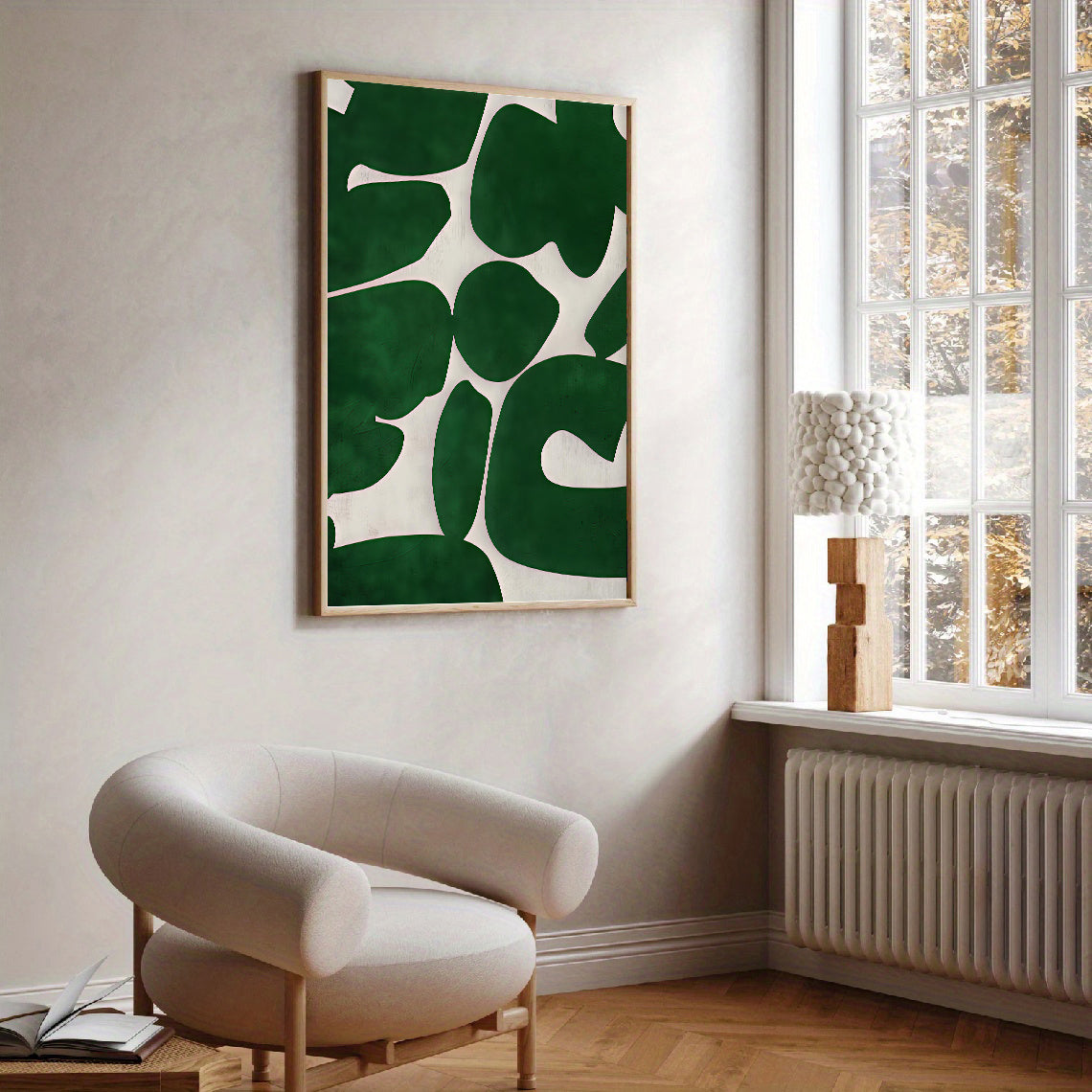 Modern interior with a green abstract leaf-patterned artwork on a white wall, a beige armchair, and a window with a view of trees.