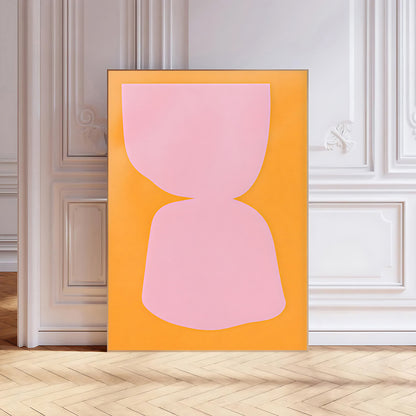 Abstract art print with a pink shape on an orange background in a room with white walls and wooden floor.