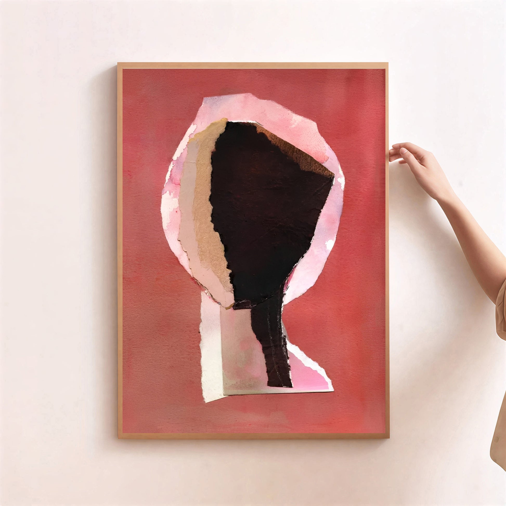 Framed abstract art piece on a wall with a hand adjusting the frame.