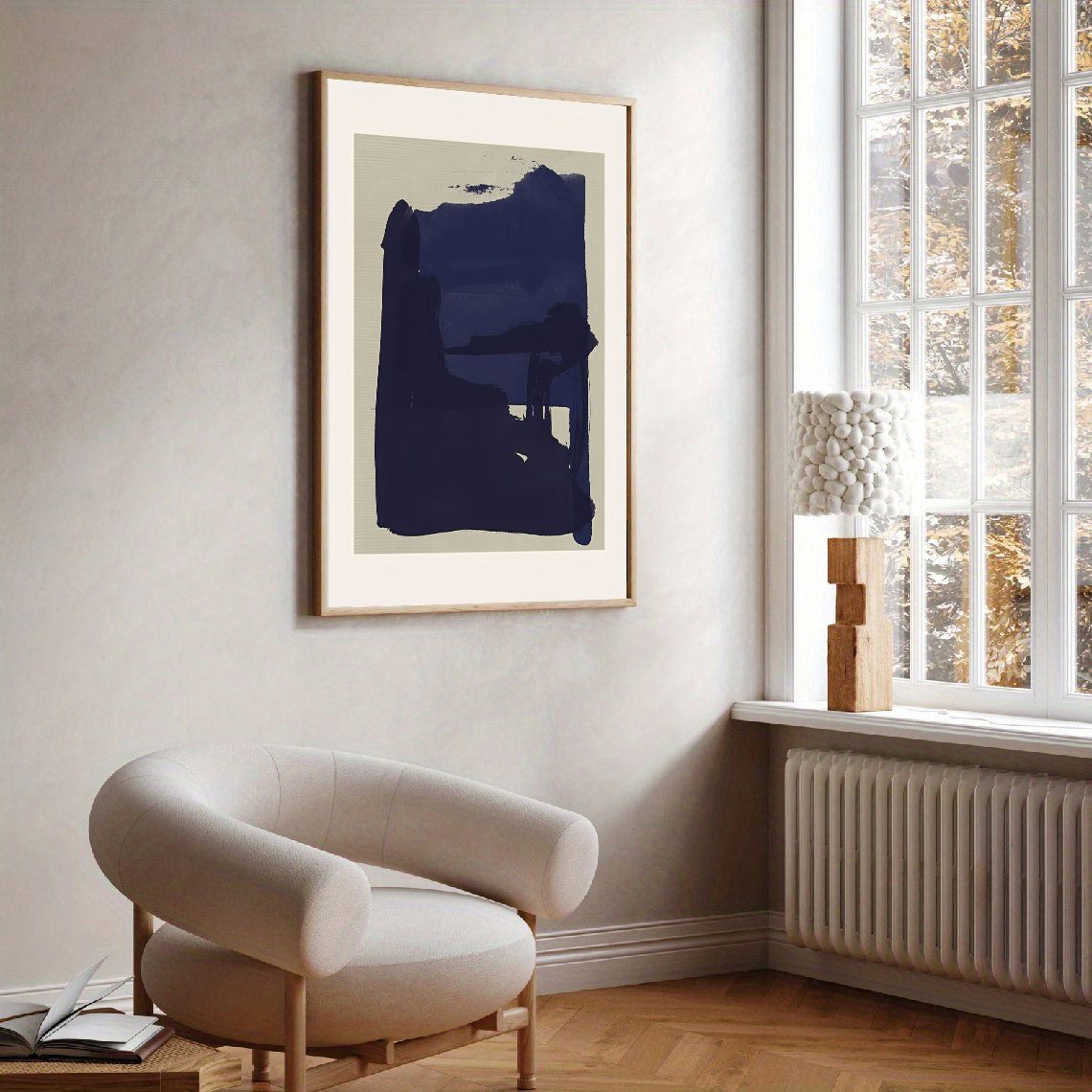 Abstract art print on a wall above a modern chair in a room with a window.