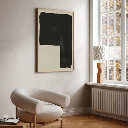 Modern interior with a beige armchair, abstract art, and a window with a view of trees.
