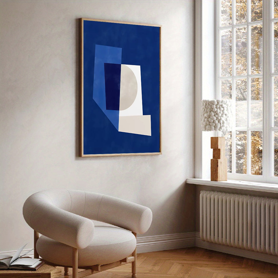 Modern interior with a blue abstract painting on the wall and a beige armchair.