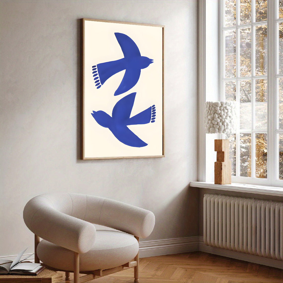 Framed artwork of blue birds on a white wall above a modern chair.