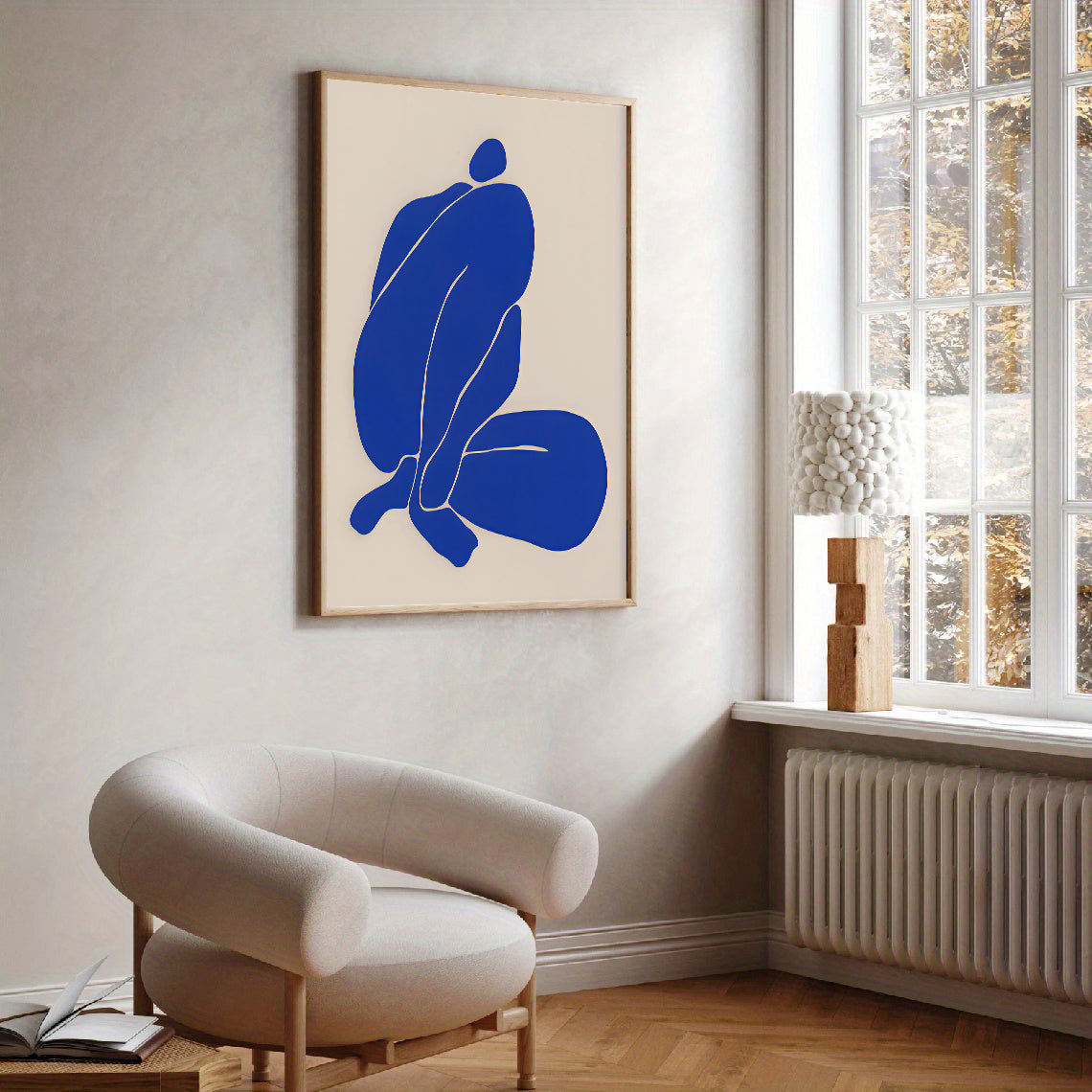 Modern interior with a blue abstract painting on a wall and a beige armchair.