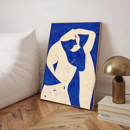 Abstract artwork of a nude figure on a blue background in a room with a lamp and books.