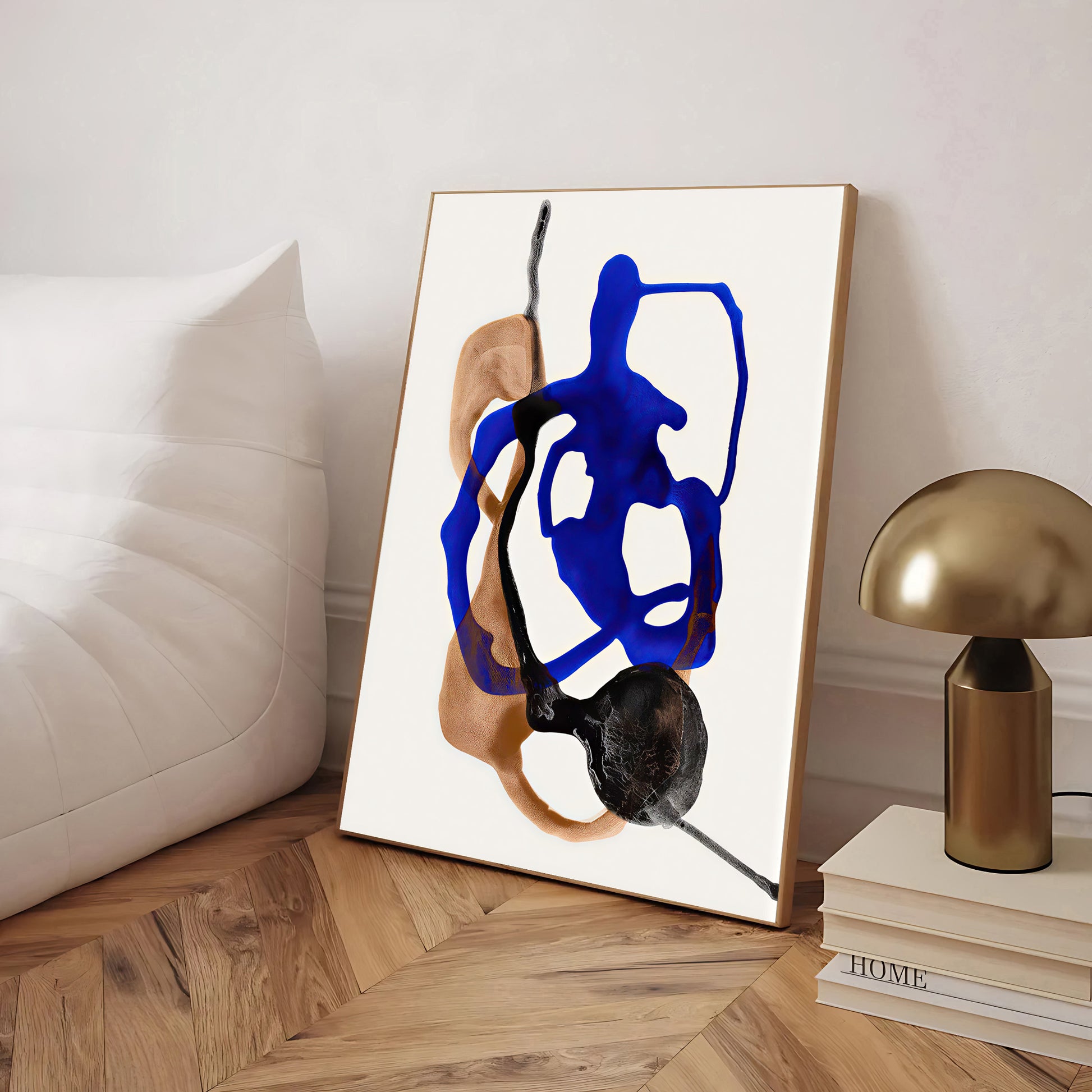 Abstract art piece on a wooden floor with a lamp and books in the background