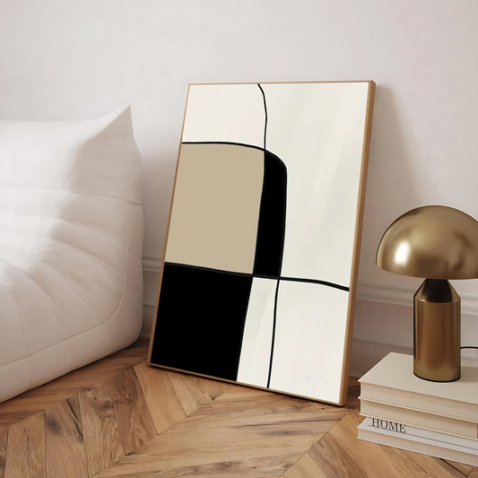 Abstract art piece on a wall next to a gold lamp and books on a wooden floor.