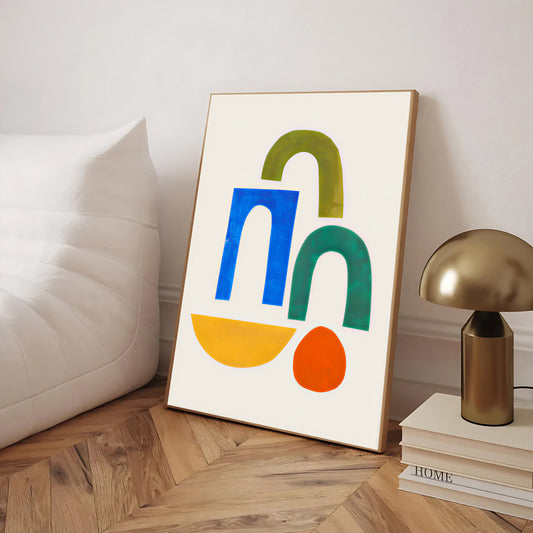 Colorful abstract art print on a wooden floor with a lamp and books in the background