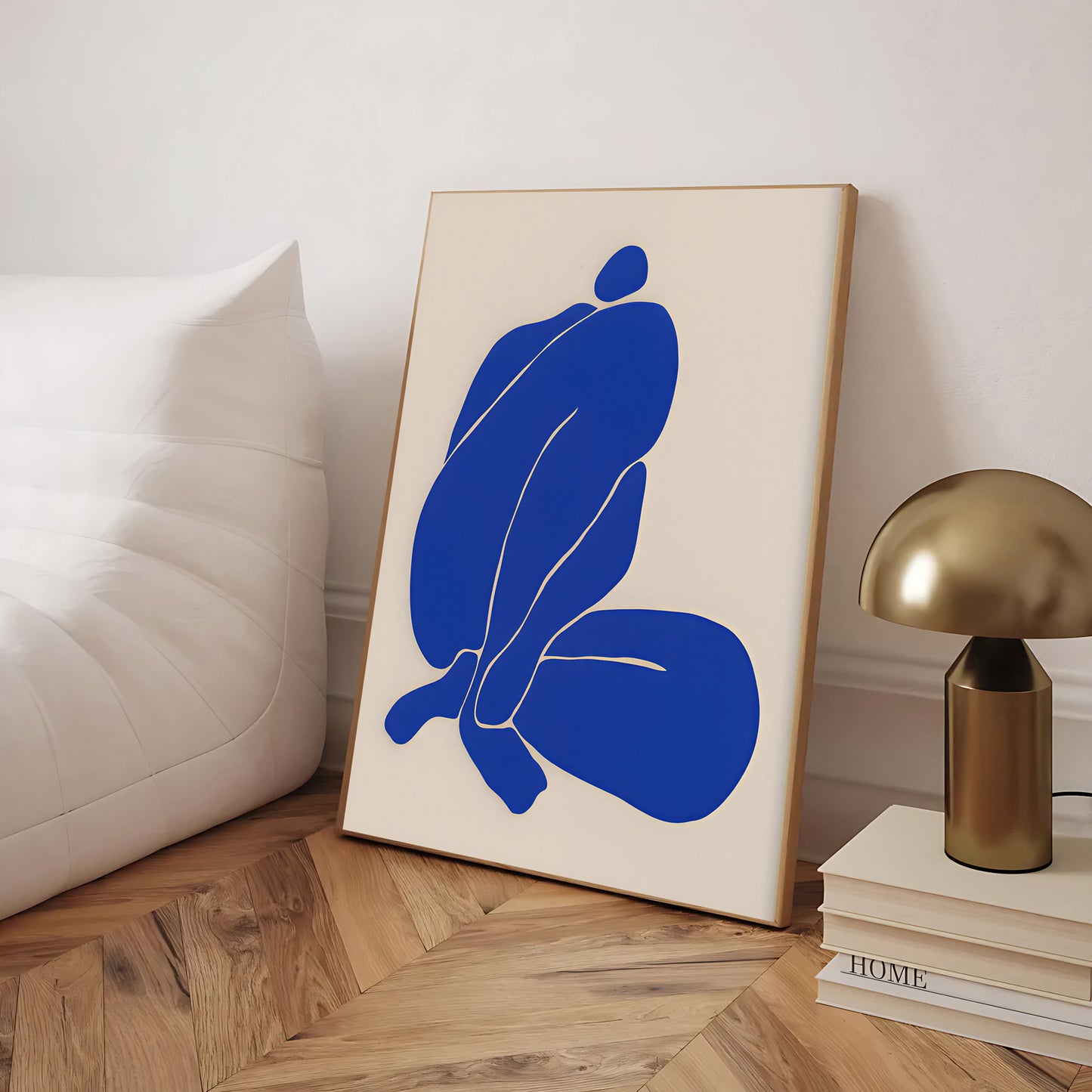 Abstract art print with blue shapes on a beige background, placed on a wooden floor.