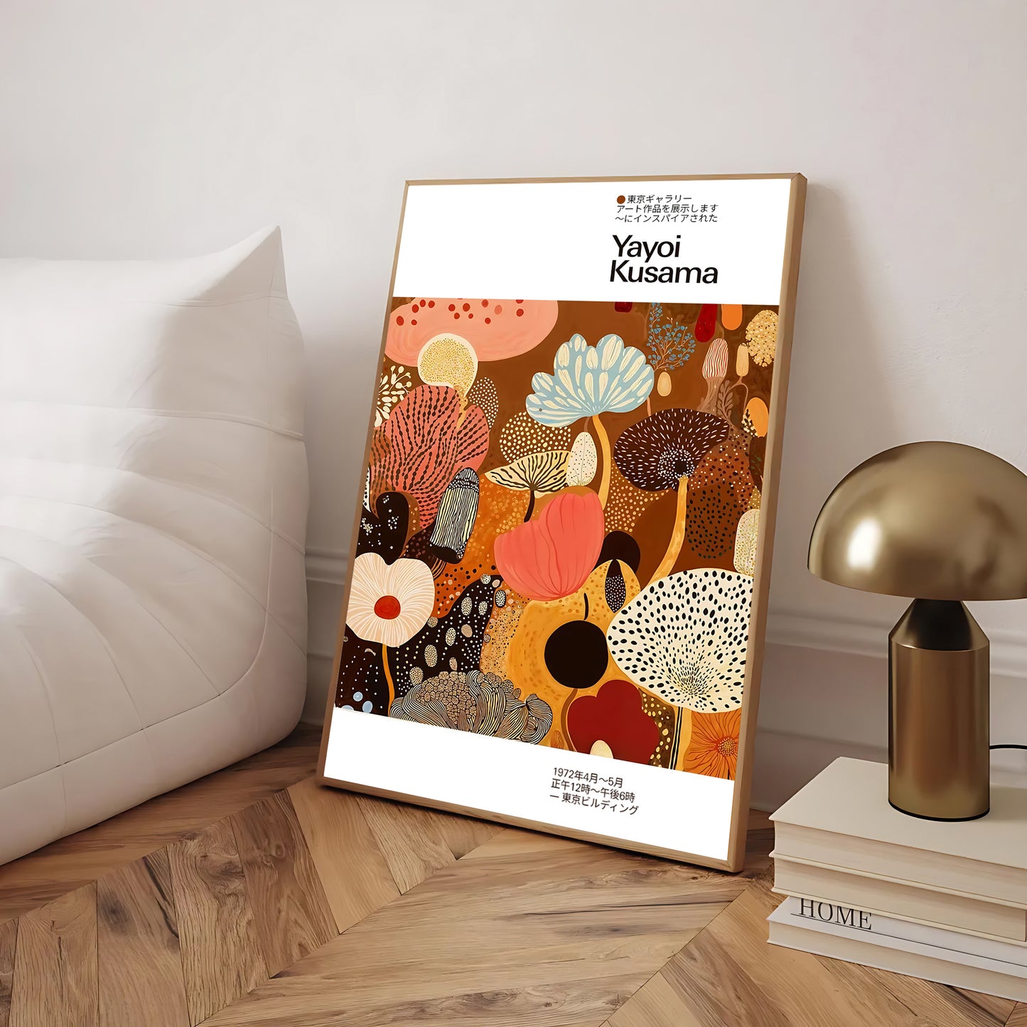 Framed artwork by Yayoi Kusama on a wooden floor with a lamp and books in the background