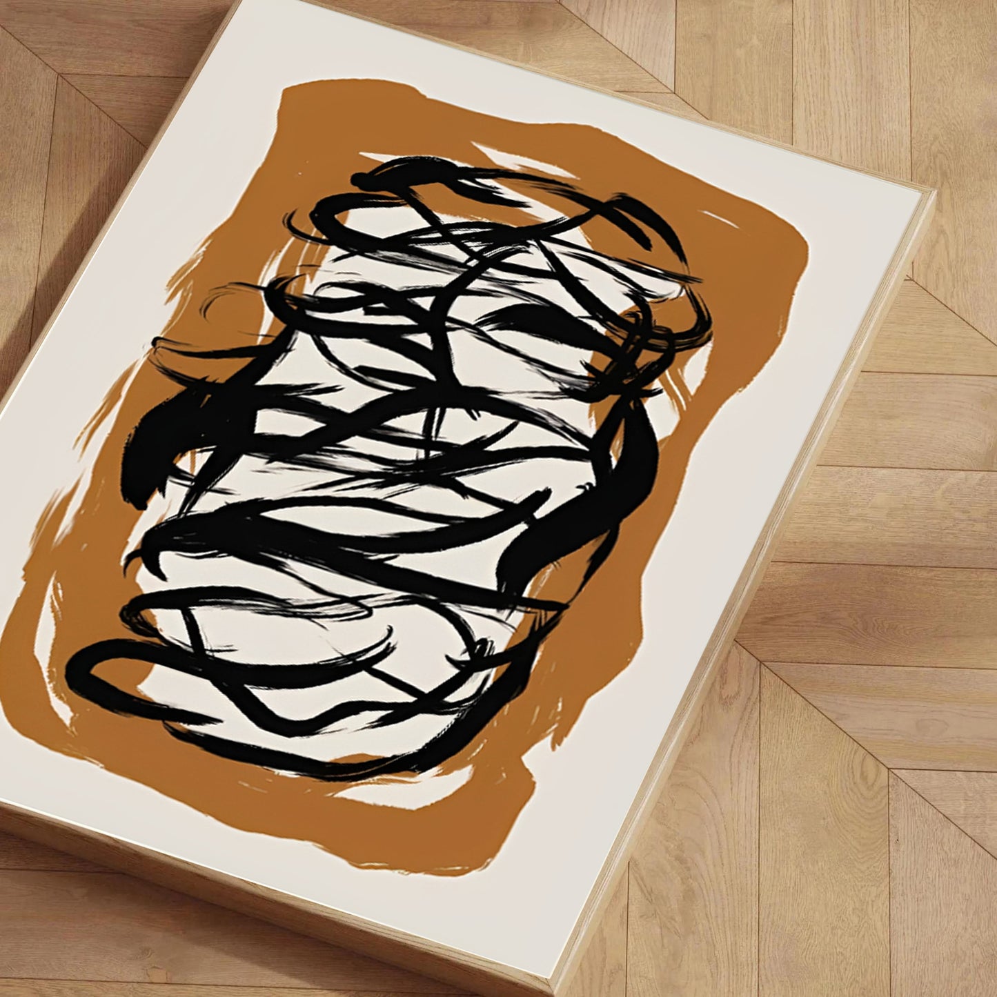 Abstract black brushstroke art on a white background with brown border on a wooden floor.