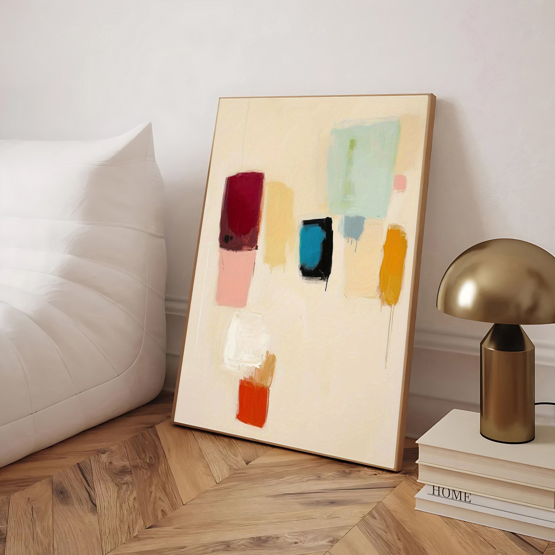 Abstract art piece on a wooden floor with a lamp and books in the background