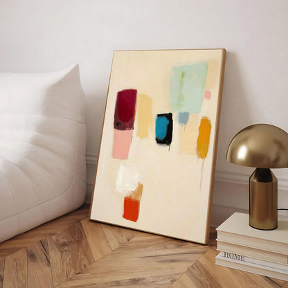 Abstract art piece on a wooden floor with a lamp and books in the background