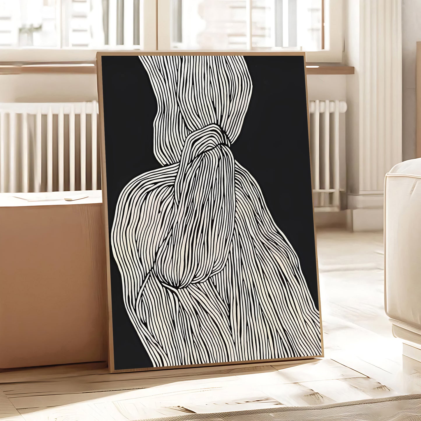 Framed abstract art piece with black background and white lines on a wooden floor.