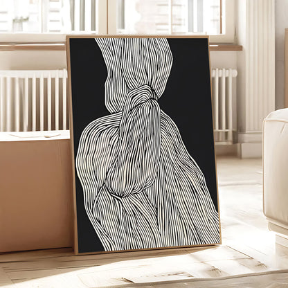 Framed abstract art piece with black background and white lines on a wooden floor.